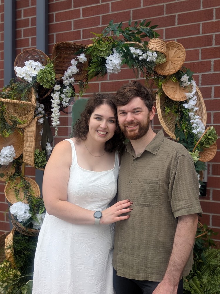 Nathan and Sadie smiling under a floral arch
